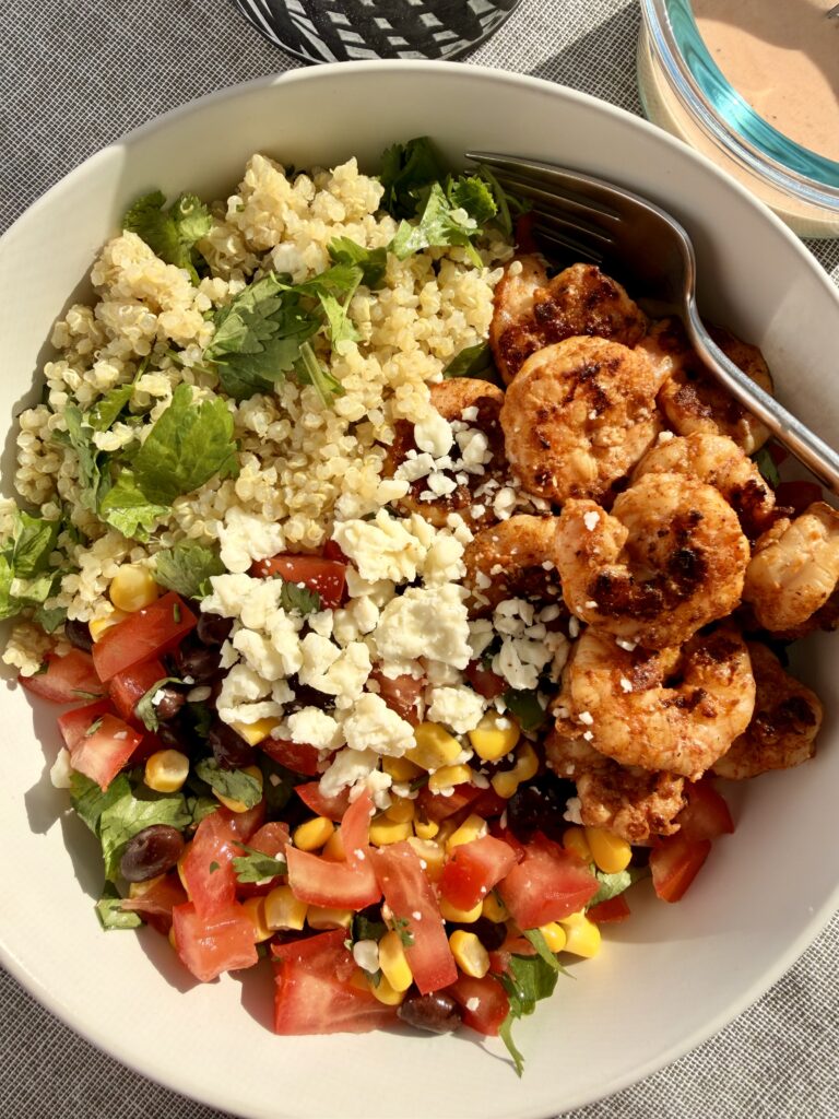Chili-lime shrimp bowl with cilantro-lime quinoa, bean-corn pico de gallo, avocado, and creamy chipotle ranch served in a bright, colorful bowl.