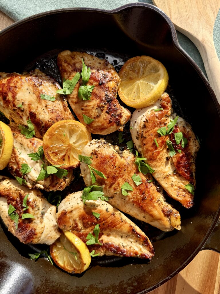 Pan-fried lemon chicken breast with golden crisp edges in a skillet, bright and juicy for salads or meal prep.